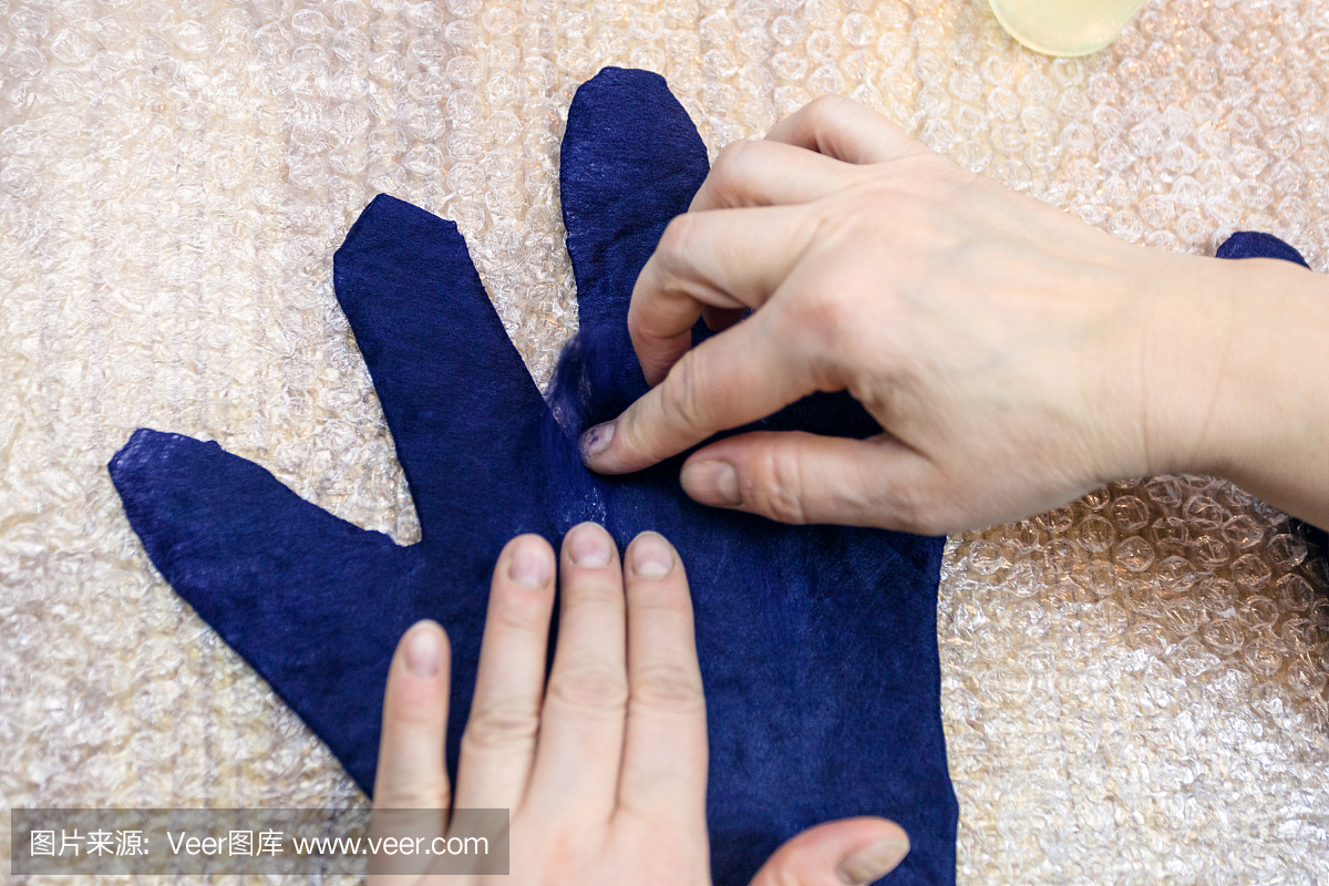 工匠在湿手套的手指上添加纤维
